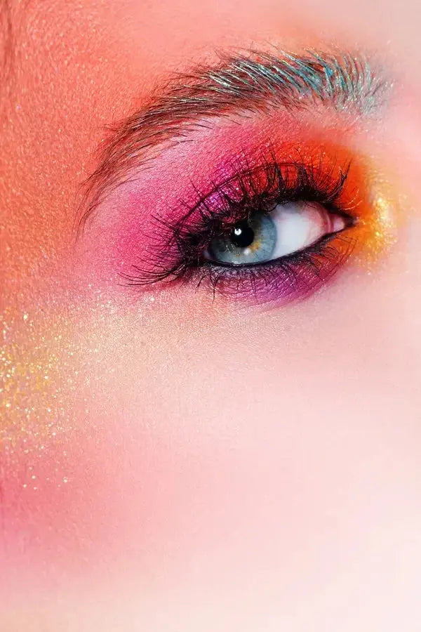 Close-up of eye with vibrant pink, orange, and purple eyeshadow and long lashes on fair skin