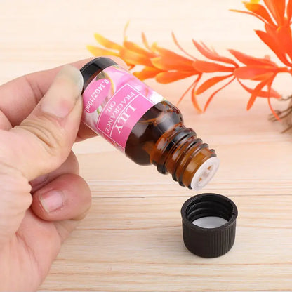 Hand holding a small brown bottle with a pink label on a wooden surface.