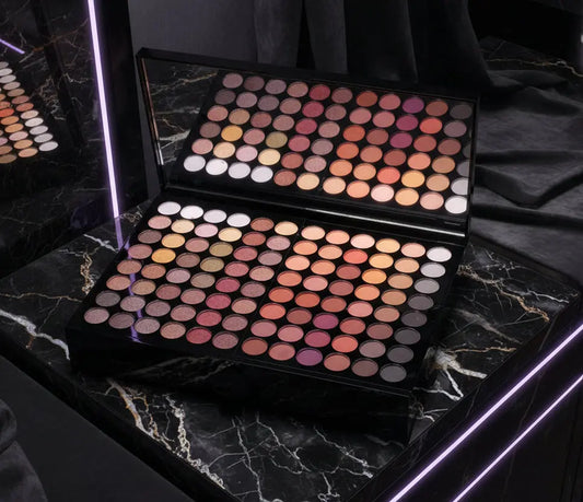 Open makeup eyeshadow palette with a variety of warm and neutral shades including browns, reds, and oranges