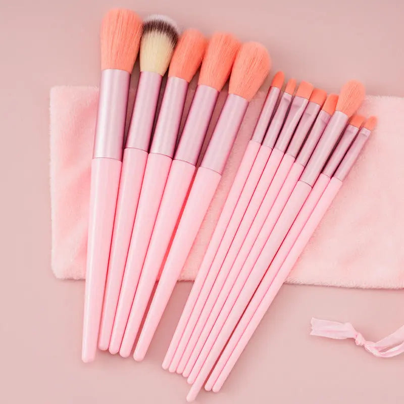 Set of pink makeup brushes with soft bristles on a pink cloth and pale pink background