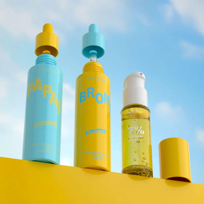 Three skincare bottles with colorful caps against a blue sky background