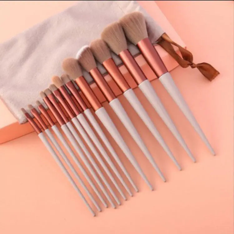 Set of 12 white handle makeup brushes with rose gold ferrules on peach background with white pouch
